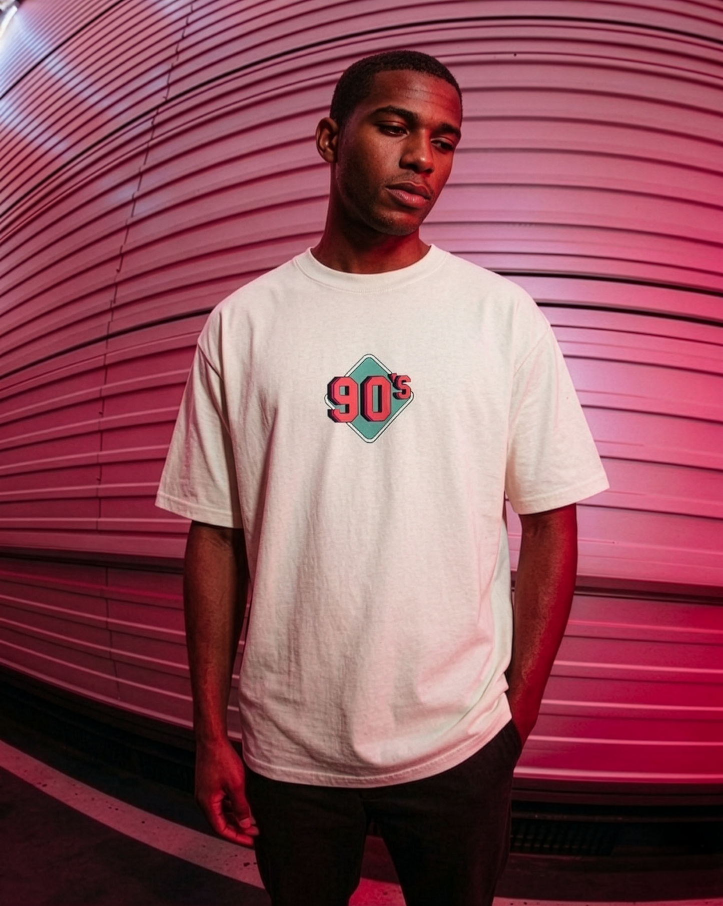 Person wearing a white t-shirt with '90s' design against a pink background