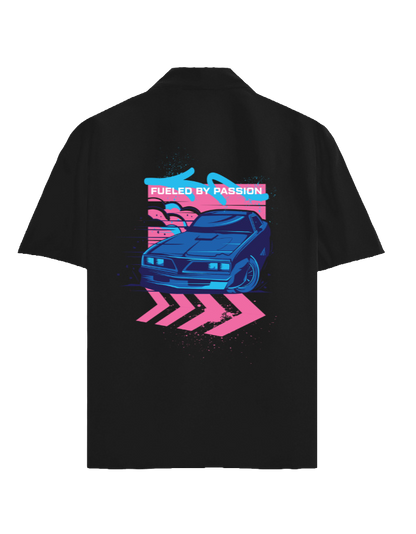 A black short-sleeve button-up shirt shown from the back, featuring a large graphic print of a blue sports car with pink and blue neon-style text and arrow shapes.