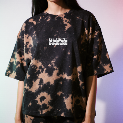 Person wearing a brown tie-dye t-shirt with 'BLAZE COUTURE' EMBROIDERED logo on a white background with light purple lighting