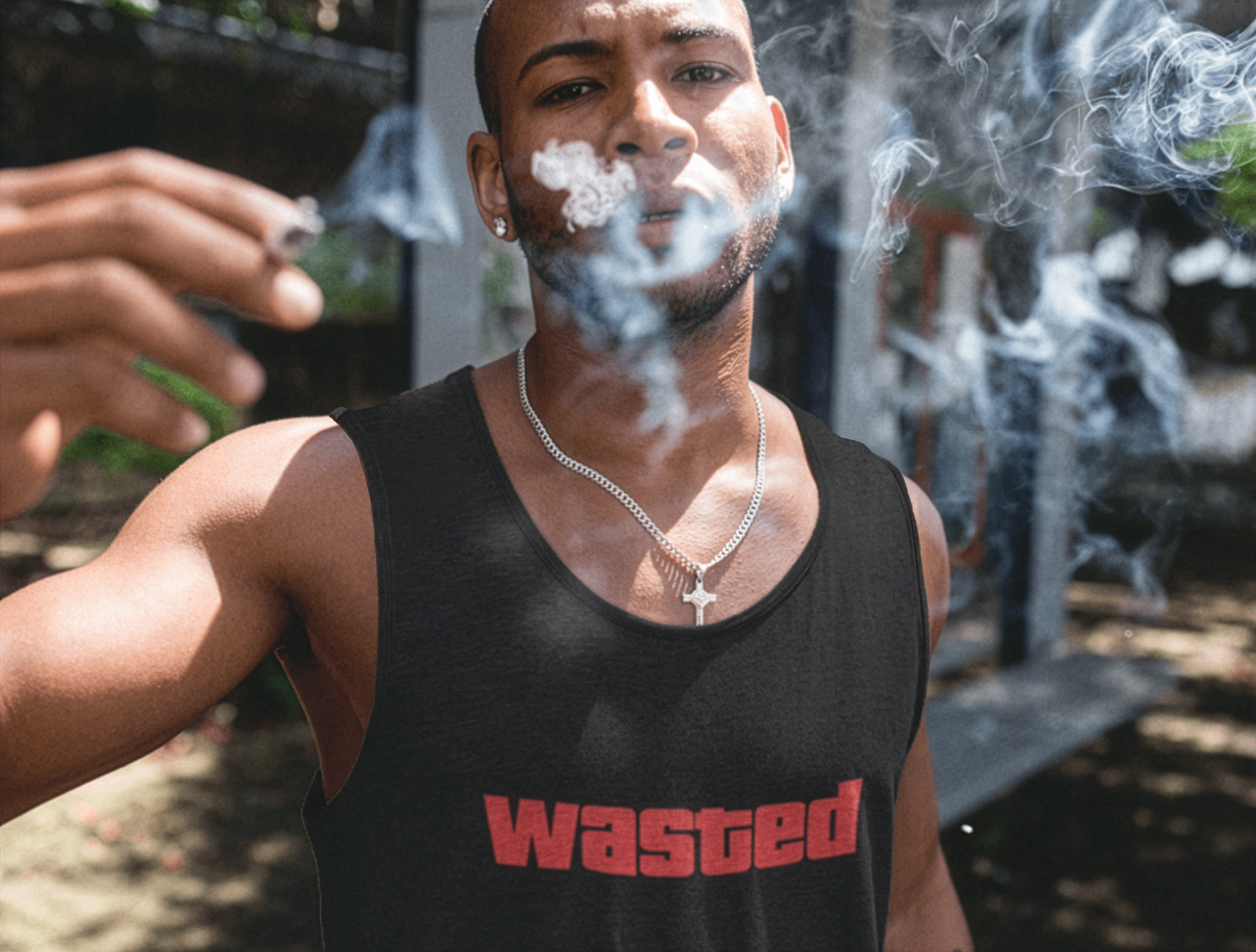 Man wearing a black tank top with 'wasted' text, smoking an e-cigarette outdoors.